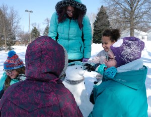 Girls build a snow penguin