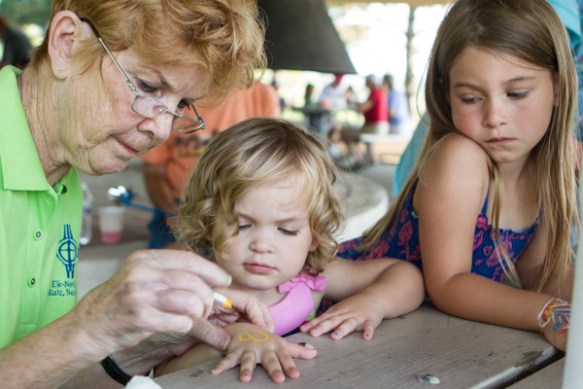 Woman painting flower on girls hand.